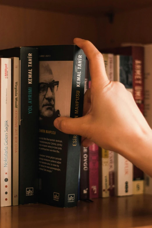 a hand is holding a book on a shelf