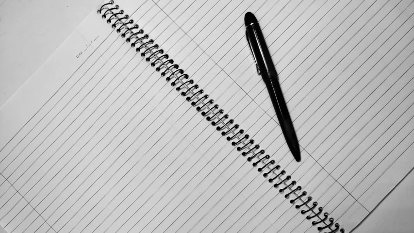 a notebook with pencil lying on top