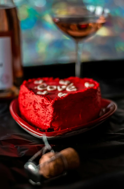 a red heart cake with wine in the background