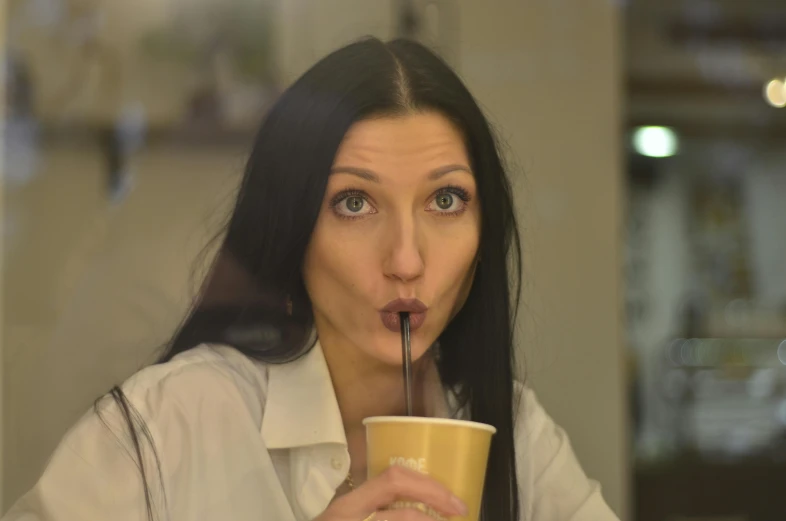 a woman is drinking from a cup in front of her