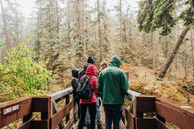 three people with backpacks walking along a bridge