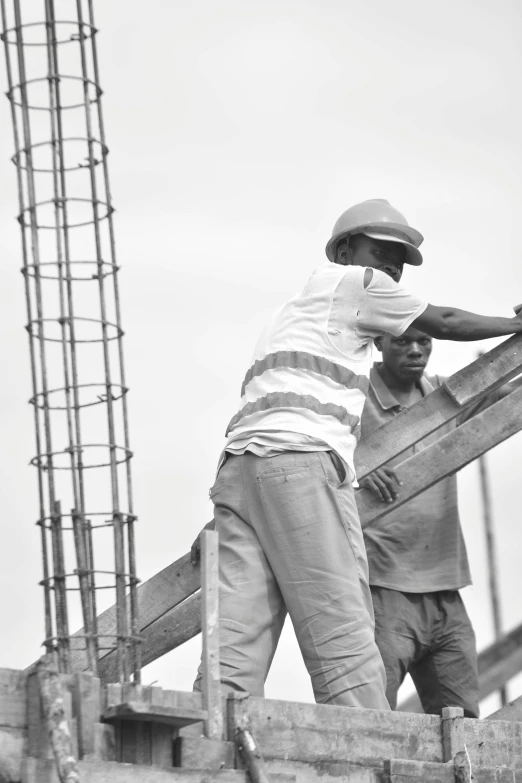 two men standing on a wooden structure that is under construction