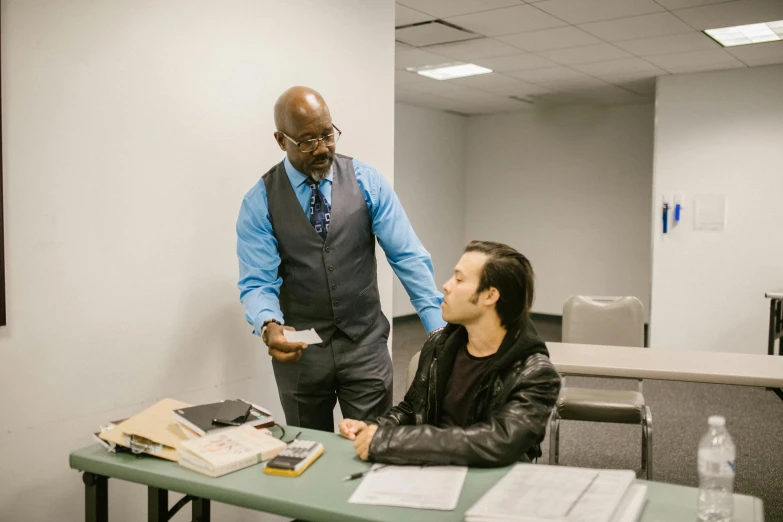 a man in a suit talking to another person at a desk