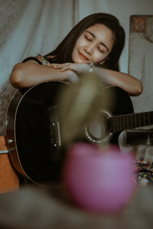a woman in bed with her face down holding a guitar