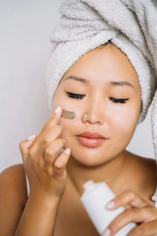 a woman applying foundation on her face with a white towel