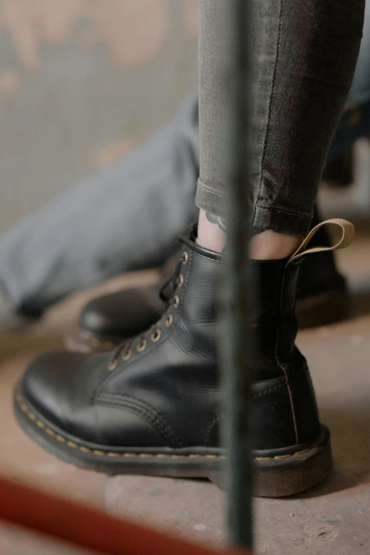 the man's legs are shown as he sits near a black shoe