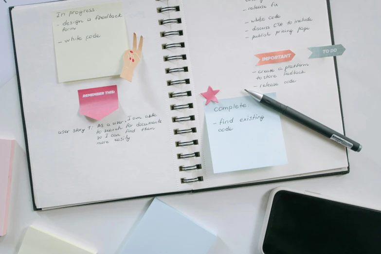 an opened planner book next to a phone and pen