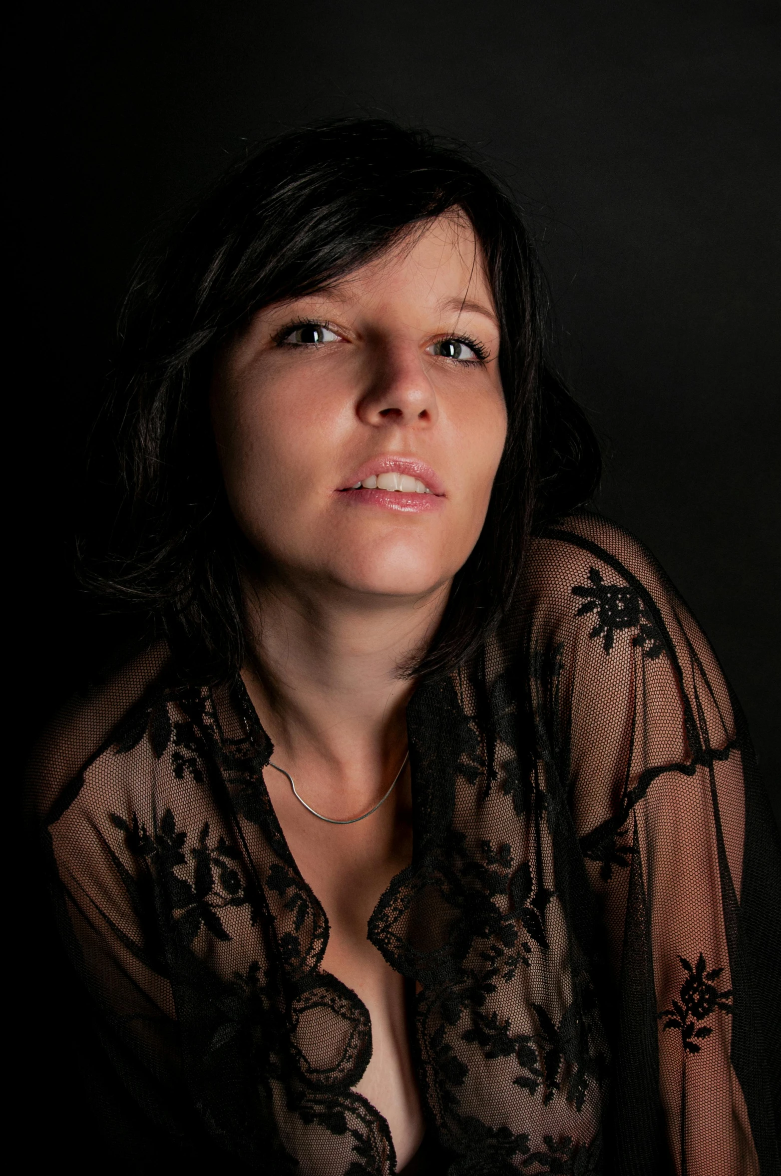 a woman sitting in a dark room with her head turned and looking away