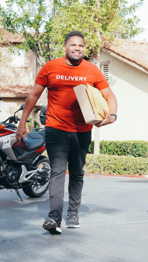 a man carrying a box walks down the street