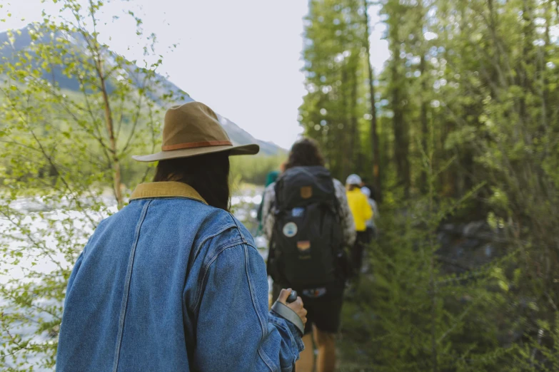 people are walking beside a pond in the woods