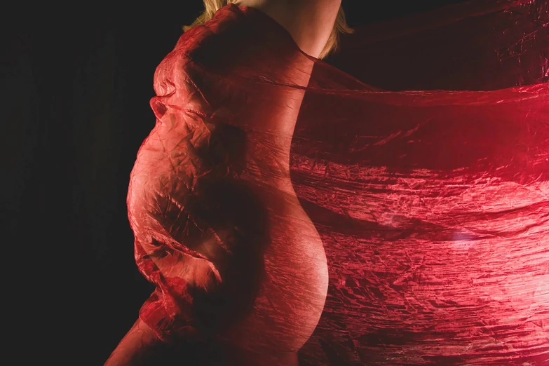 pregnant woman in red dd dress poses for picture