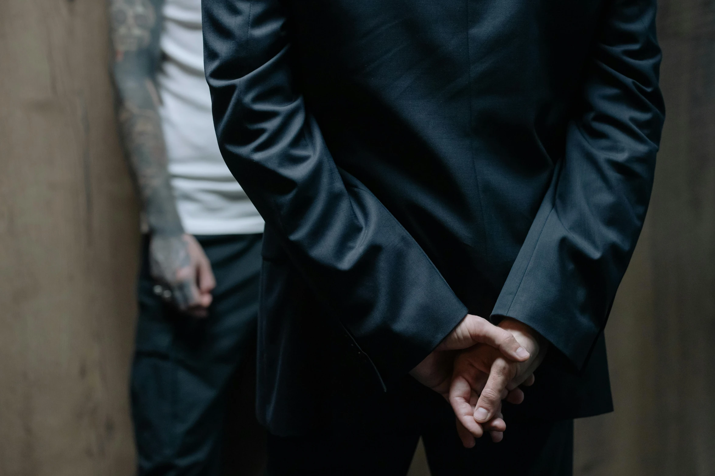 a man in a tuxedo, his hands behind his back