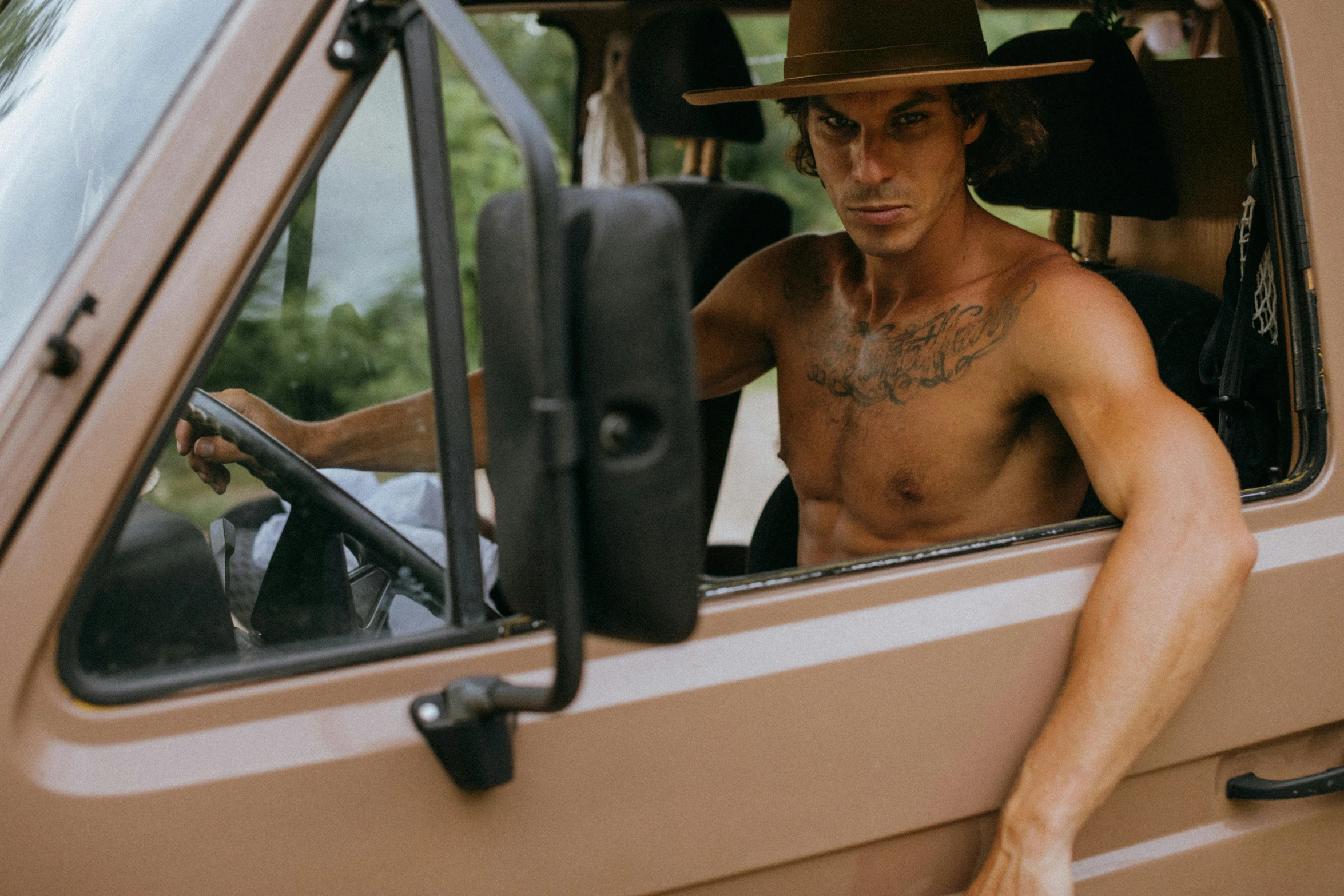 man with  and hat sitting in the driver's seat of a vehicle