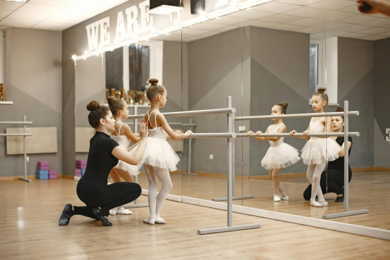 several young ballerinas in a dance class and some people in a mirror