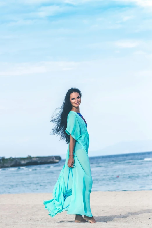 woman wearing blue walking on beach next to water