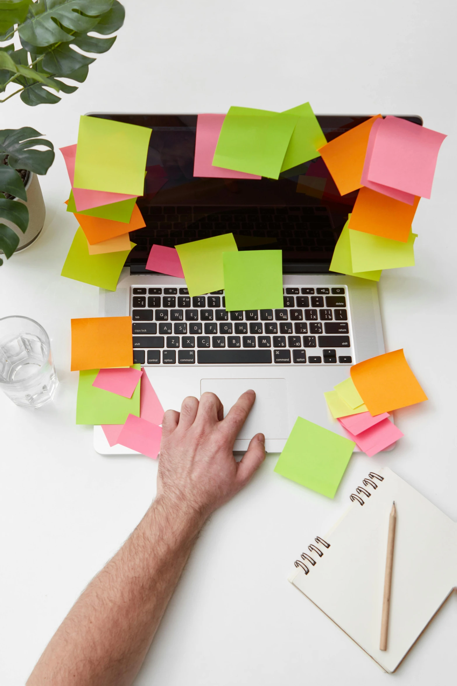 someones hands and a computer with sticky notes on them