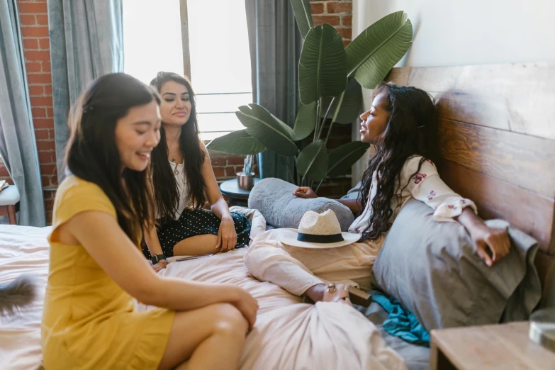 a group of three girls sitting on a bed and talking