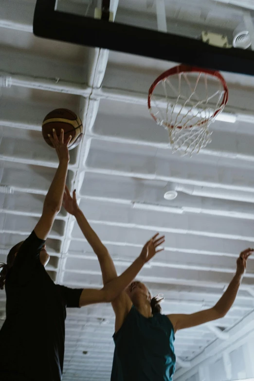 two men playing basketball while wearing green uniforms