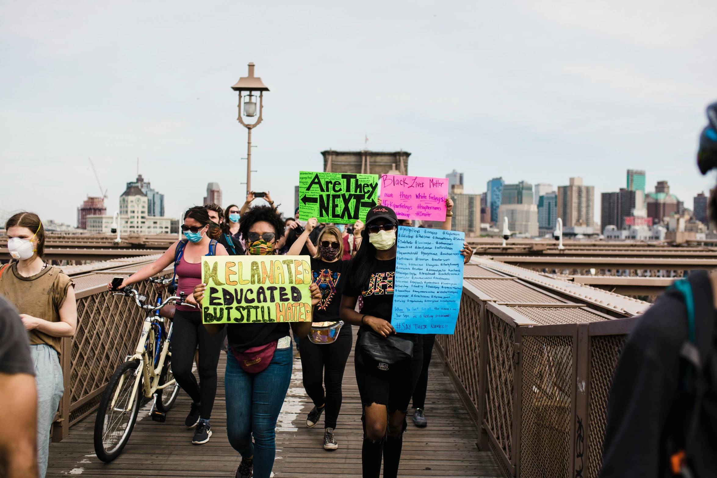 a group of people holding signs and standing on a bridge