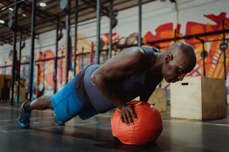 a man on a ball doing h ups with an orange medicine pillow