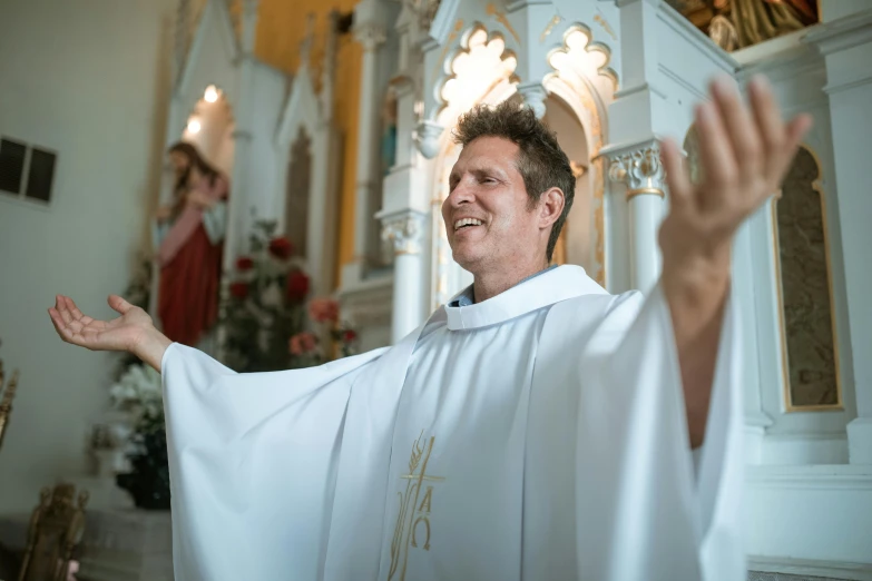 a man in a priest's outfit with his hands outstretched