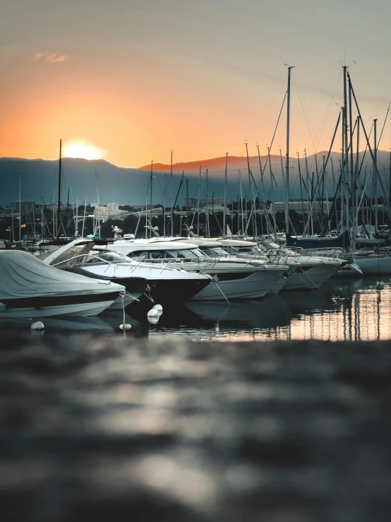 the sun is setting over boats on the water