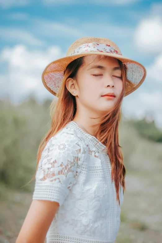 a girl wearing a hat standing in a field