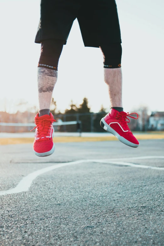 a person's legs and red sneakers are seen while standing on a street