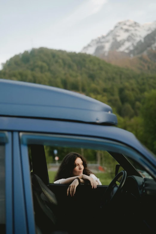 a woman sits in the back seat of a car looking out a window