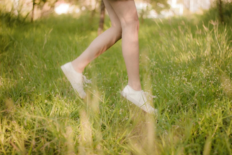 a person with white shoes walking in tall grass