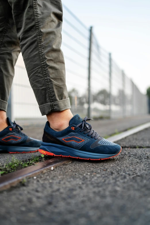 a man's feet wearing blue shoes and grey pants