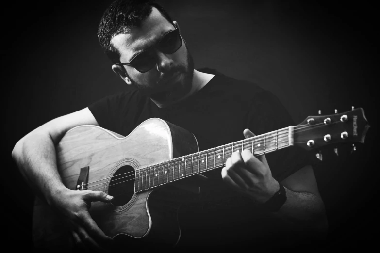 man playing an acoustic guitar in black and white