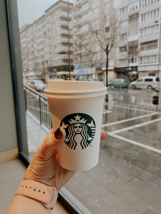 a woman holding up a coffee cup to take it