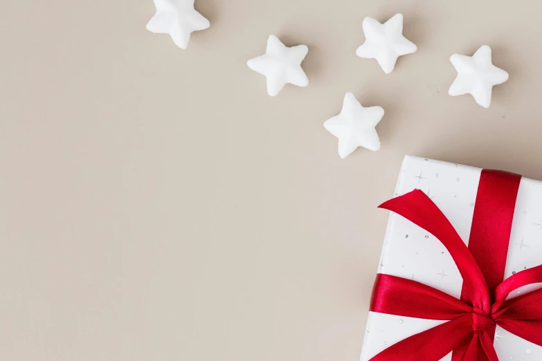 wrapped gift with ribbon laying beside five white stars