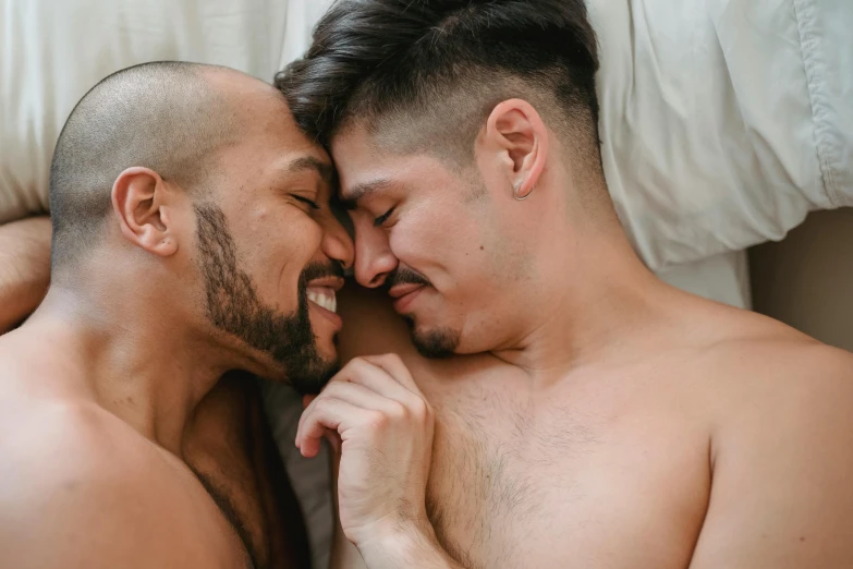 two men laying next to each other in the same bed