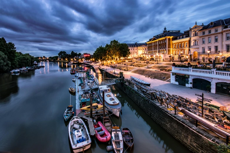 many boats docked next to a city with lights on