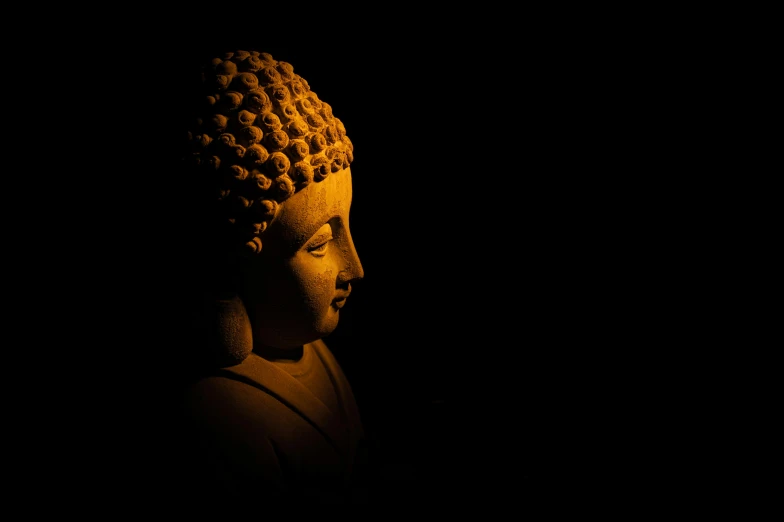 the head of a buddha statue lit by a candle