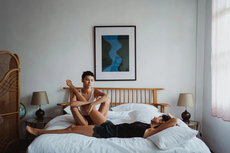 two people laying on the bed and posing