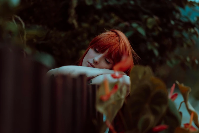 a girl leaning her head on a fence