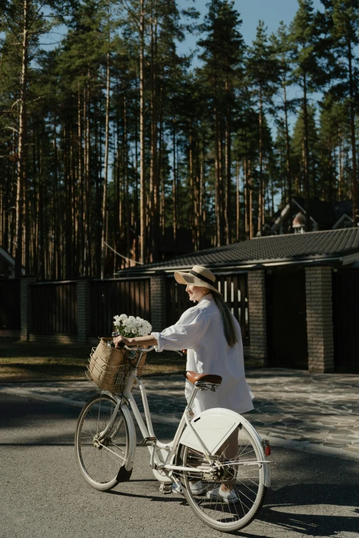 a woman in white riding a bicycle carrying a basket