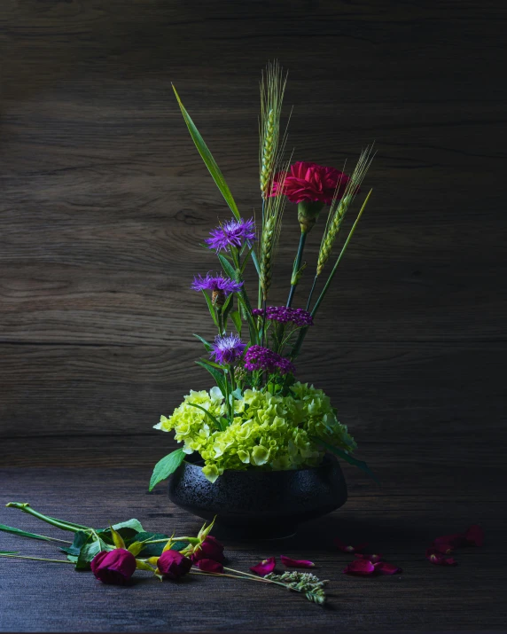 several colorful flowers are on the floor next to the vase