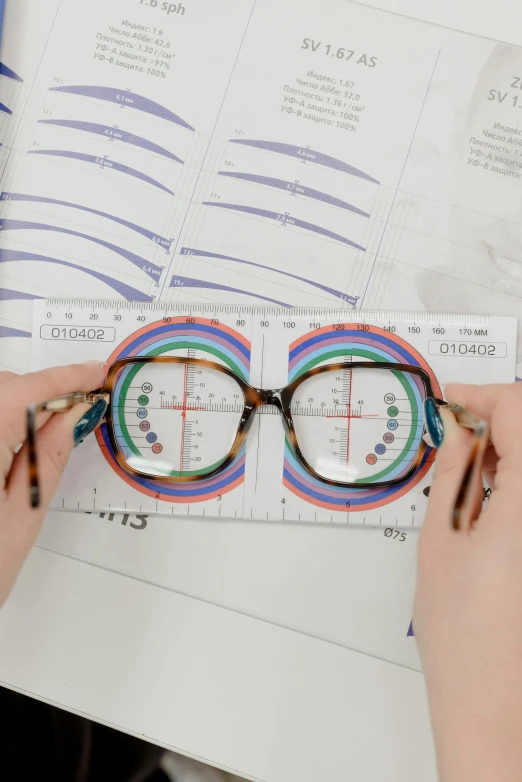a pair of hands are holding the measurements on a pair of reading glasses