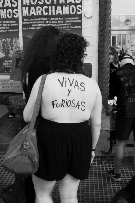 a woman with a huge shirt with spanish words tattooed on her back