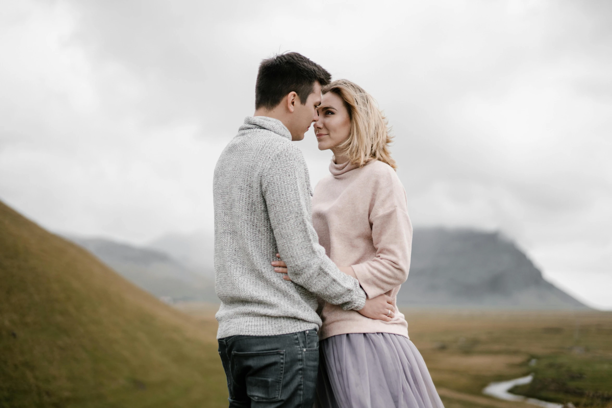 a couple stands together near the mountains