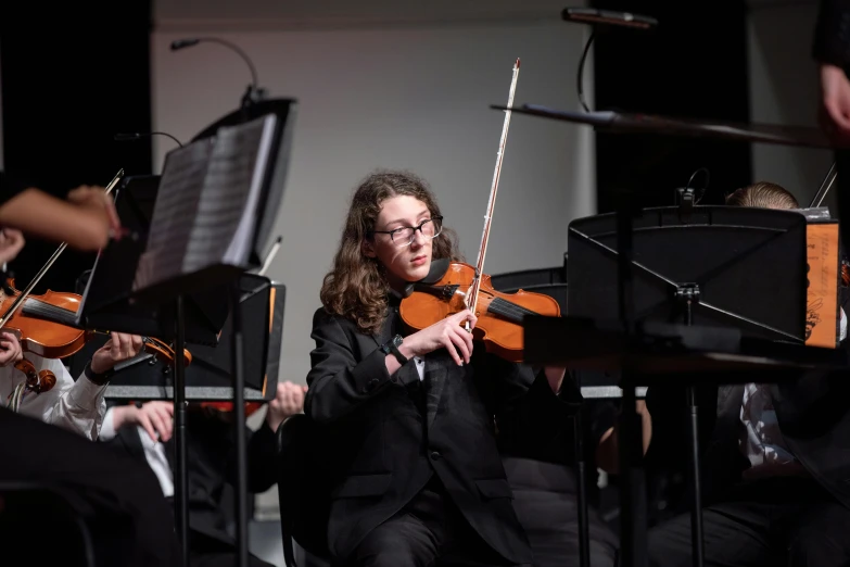 a female violinist in a black suit is playing an instrument