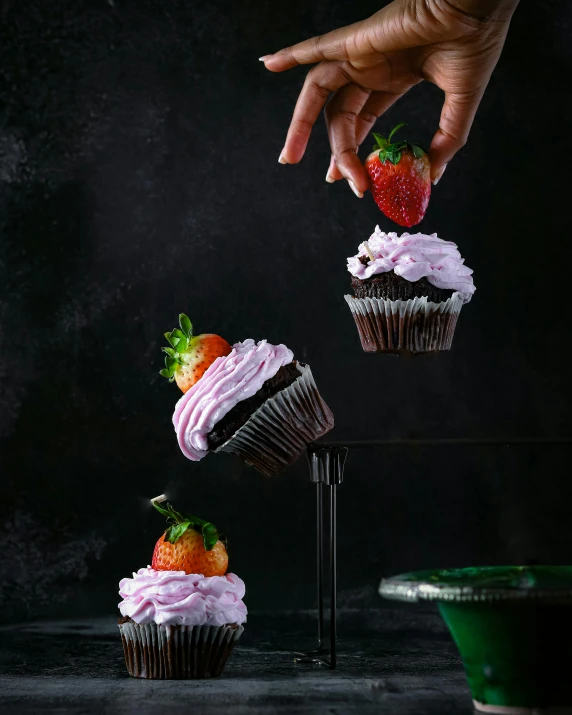 a person's hand grabbing a strawberry with icing on it