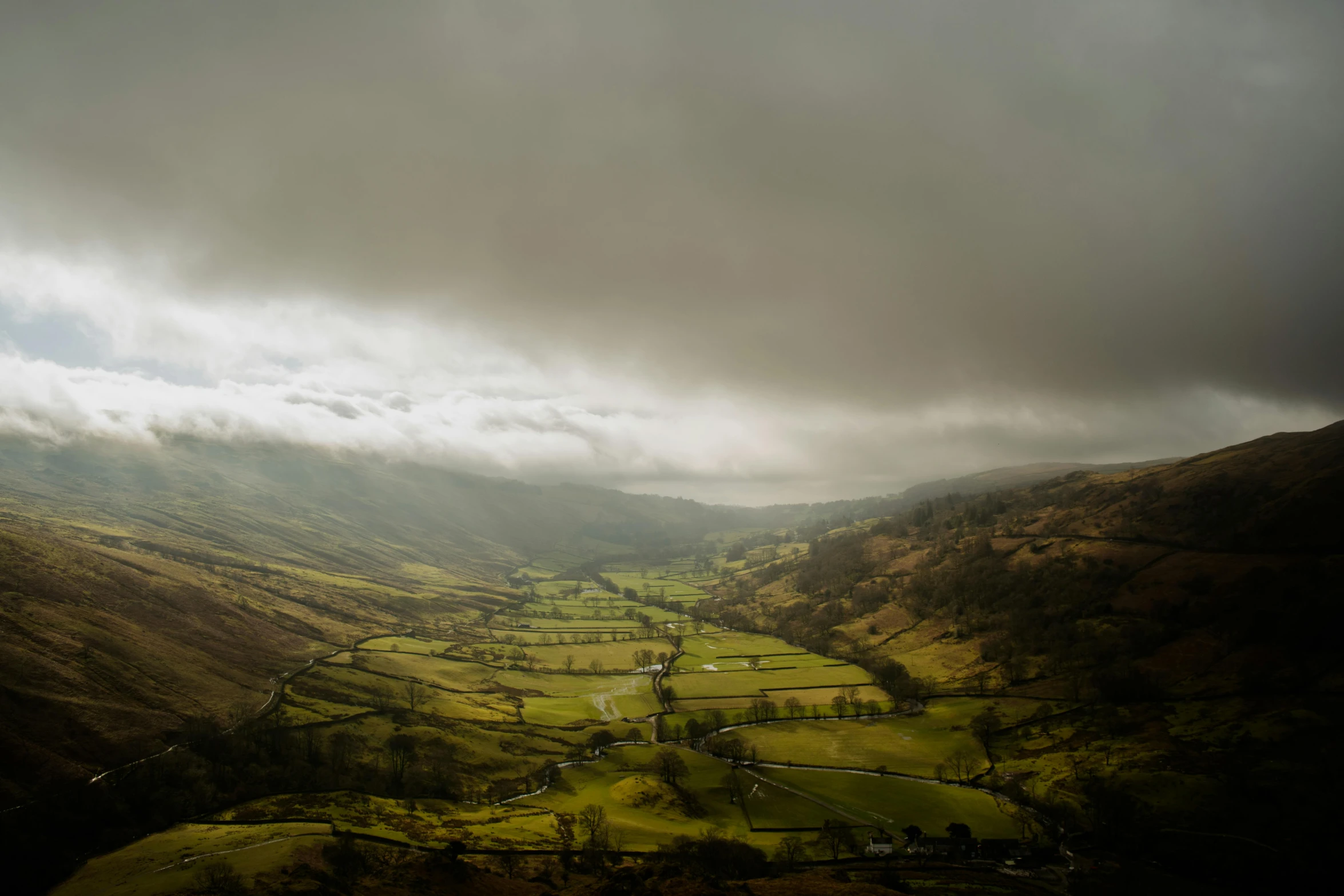 a large valley is surrounded by hills with clouds