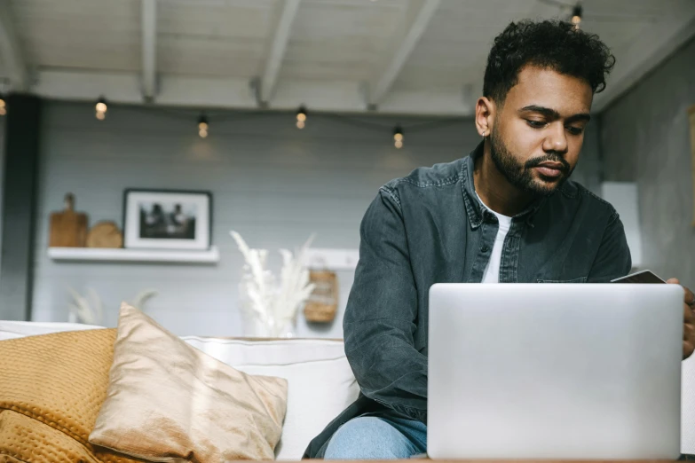 the man is using his laptop while sitting on the couch