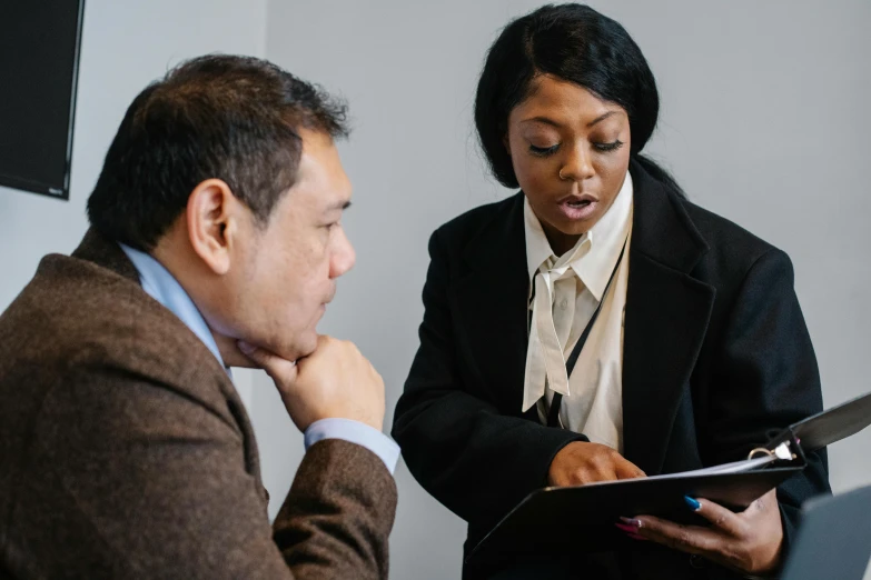 a man is standing next to a woman with an open folder