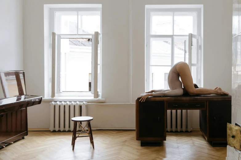 a woman in leotards is laying on a chair in front of two windows